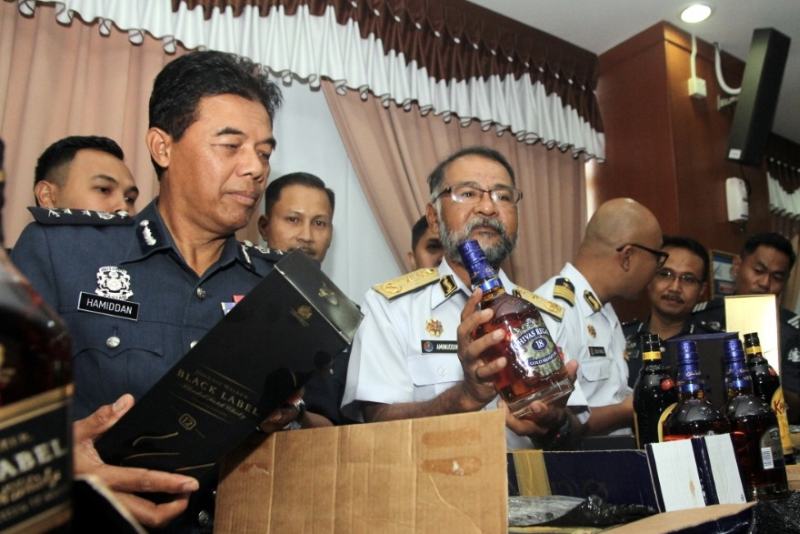 Johor Customs Department director Mohammad Hamiddan Maryani (left) and Johor MMEA director First Admiral Aminuddin Abdul Rashid (second left) with the seized contraband liquor at Menara Kastam in Johor Baru today. u00e2u20acu201d Picture by Ben Tan