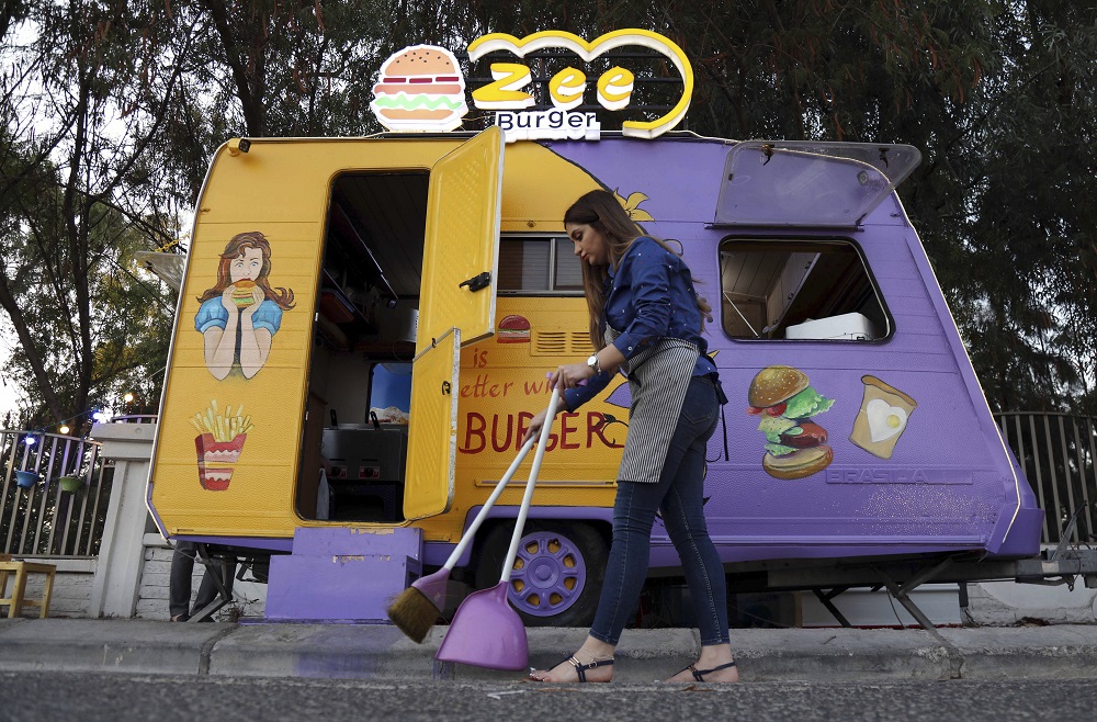 Zilan Serwud, the 22-year-old owner of the Zee Burger food truck, sweeps up the area around her truck in Arbil, the capital of the northern Iraqi Kurdish autonomous region August 17, 2019. u00e2u20acu201d AFP pic       