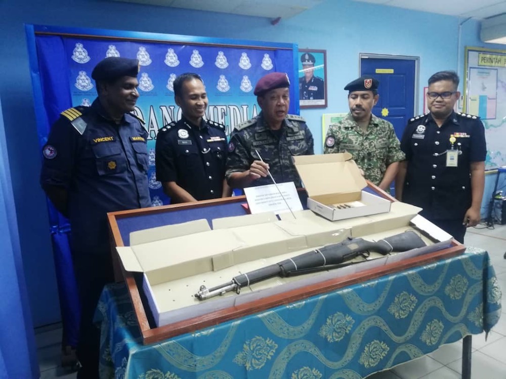 Eastern Sabah Security Commander Datuk Hazani Ghazali (centre) with the seized items including rifle from the incident last night. u00e2u20acu201d Picture courtesy of Esscom