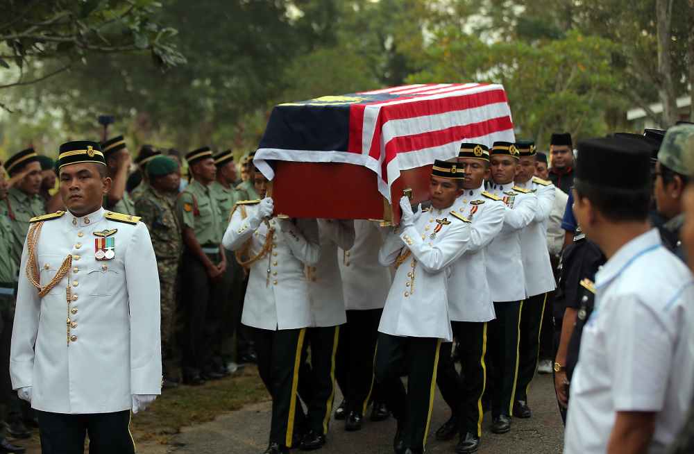 Armed Forces personnel escorted the casket that was draped with the Malaysian flag to the burial site in a silent procession.u00e2u20acu2022 Picture by Farhan Najibn