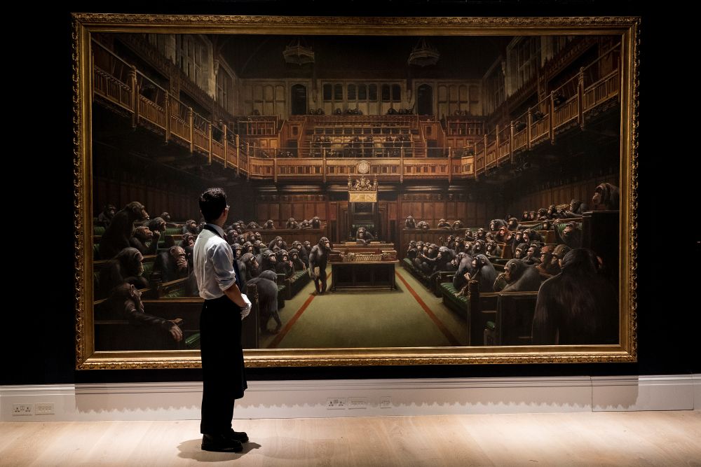 Sothebyu00e2u20acu2122s staff pose for a photograph with Banksyu00e2u20acu2122s u00e2u20acu02dcDevolved Parliamentu00e2u20acu2122 which has an estimated value of u00c2u00a31.5-2 million in a forthcoming sale in London September 27, 2019. u00e2u20acu201d Reuters pic