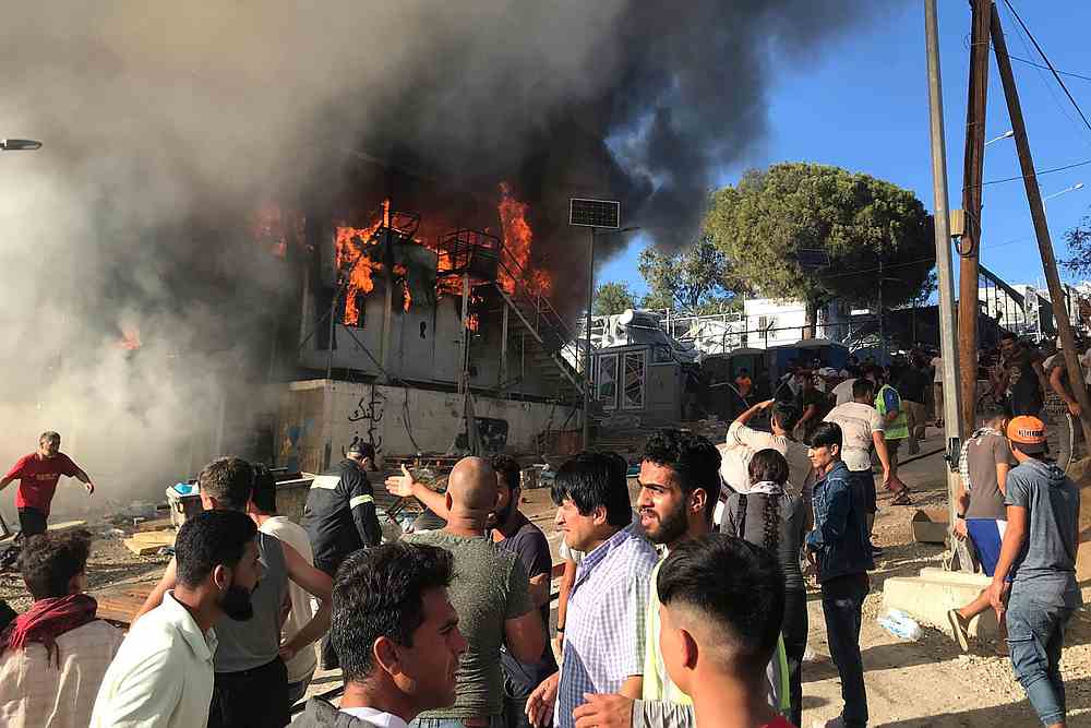 Migrants stand next to a burning container during a fire in Moria camp on the island of Lesbos, Greece, September 29, 2019. u00e2u20acu201d Ihab Abassi/handout via Reuters 