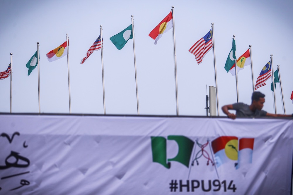 A man hangs Umno, PAS and Malaysia flags at Putra World Trade Centre in Kuala Lumpur September 12, 2019, ahead of the Muslim Unity Rally. u00e2u20acu201d Picture by Hari Anggara