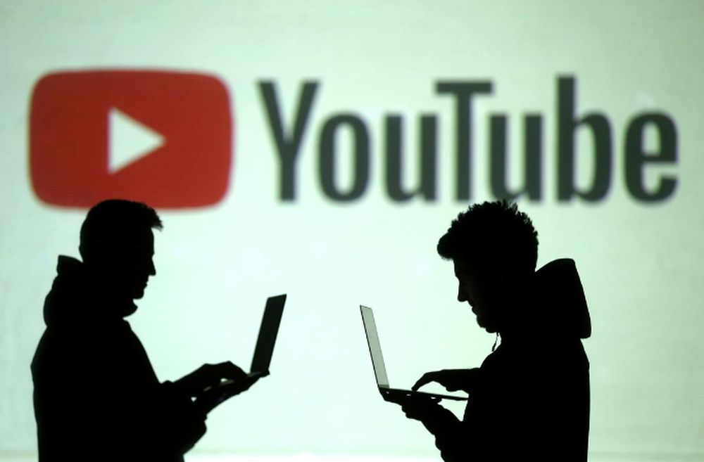 Silhouettes of mobile device users are seen next to a screen projection of YouTube logo in this picture illustration taken March 28, 2018. u00e2u20acu201d Reuters pic