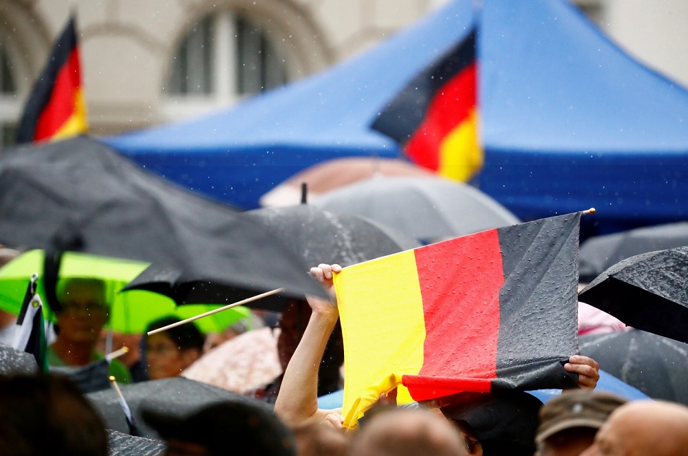 Supporters of Germany's far-right Alternative for Germany (AfD) party take shelter from rain under a German flag, during an election campaign in Cottbus, Germany July 13, 2019. u00e2u20acu201d Reuters pic