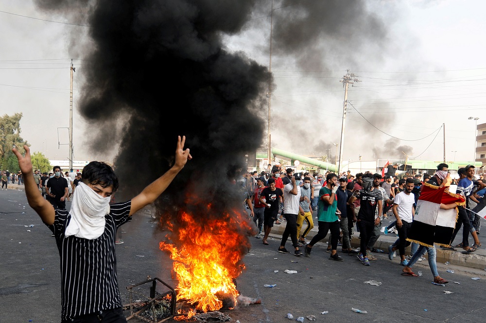 A demonstrator gestures as he stands close to burning tires blocking a road, during a protest over unemployment, corruption and poor public services, in Baghdad October 2, 2019. u00e2u20acu201d Reuters pic