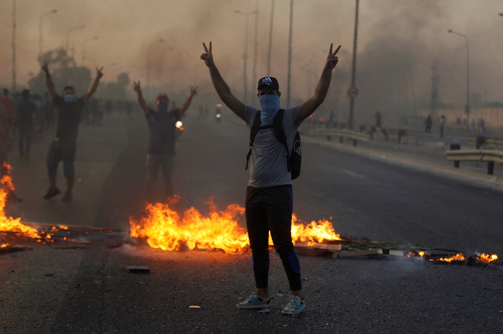 Demonstrators gesture near burning objects at a protest during a curfew, two days after the nationwide anti-government protests turned violent, in Baghdad October 3, 2019. u00e2u20acu201d Reuters pic