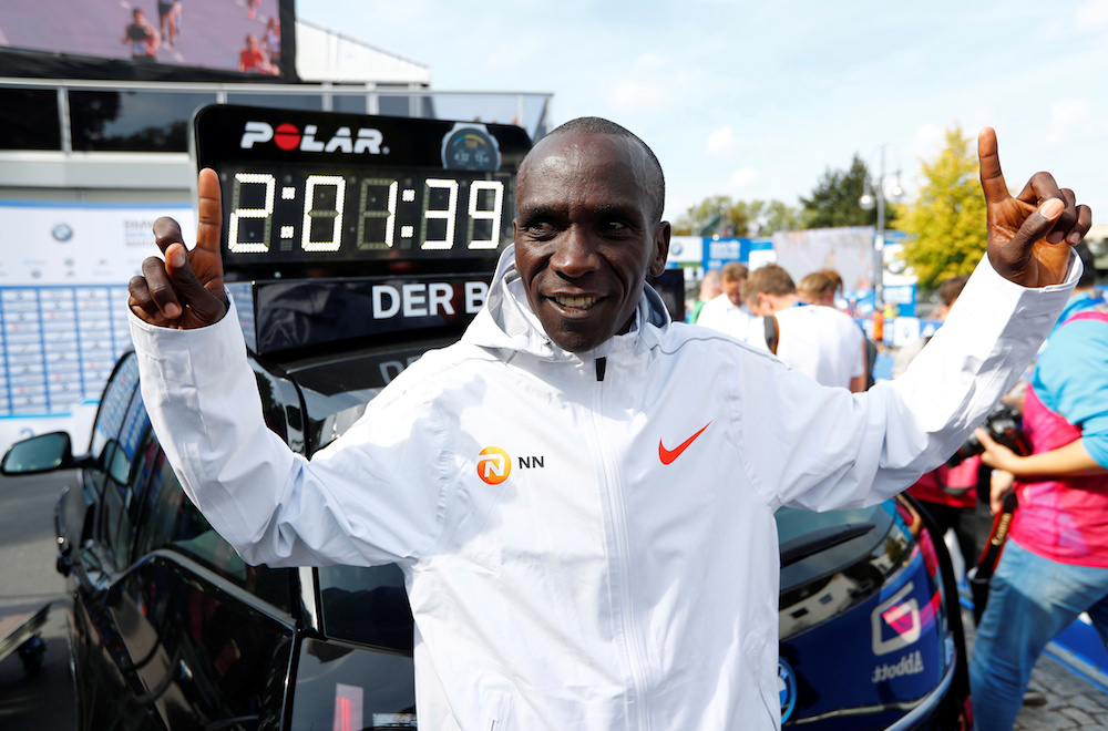 Kenyau00e2u20acu2122s Eliud Kipchoge celebrates winning the Berlin Marathon alongside a clock showing his World Record breaking time September 16, 2018. u00e2u20acu201d Reuters pic