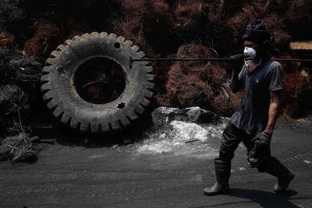 A worker passes steel wires and a tyre at a tyre pyrolysis plant in Kulai, Johor August 7, 2019. u00e2u20acu201d Reuters pic