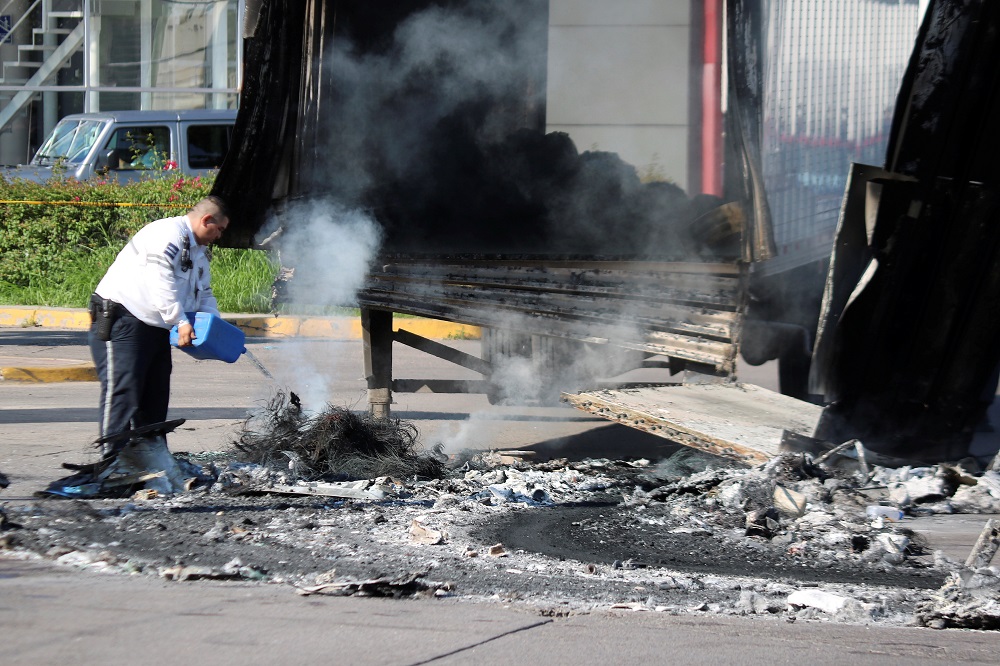 A police officer pours water on the burnt wreckage of a truck a day after cartel gunmen clashed with federal forces, resulting in the release of Ovidio Guzman from detention in Culiacan, Mexico October 18, 2019. u00e2u20acu201d Reuters pic