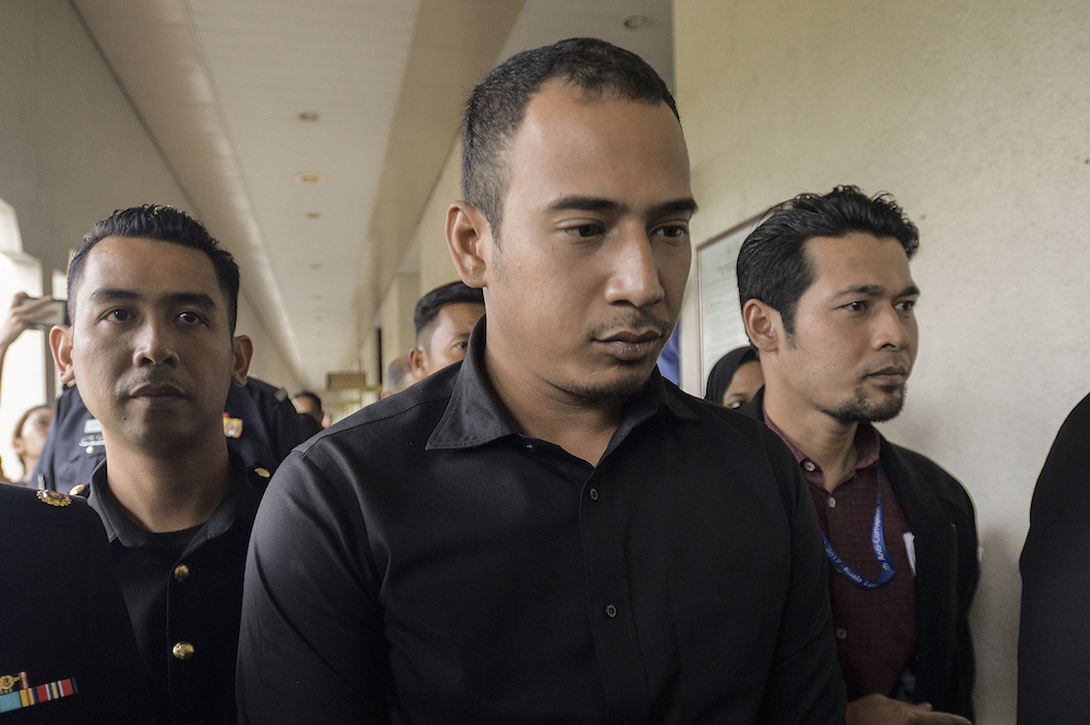 Abdulazeez Wan Ruslan, son of former Companies Commission of Malaysia (SSM) CEO, Datuk Zahrah Abd Wahab Fenner, is escorted by police at the Kuala Lumpur Sessions Court October 2, 2019. — Picture by Miera Zulyana