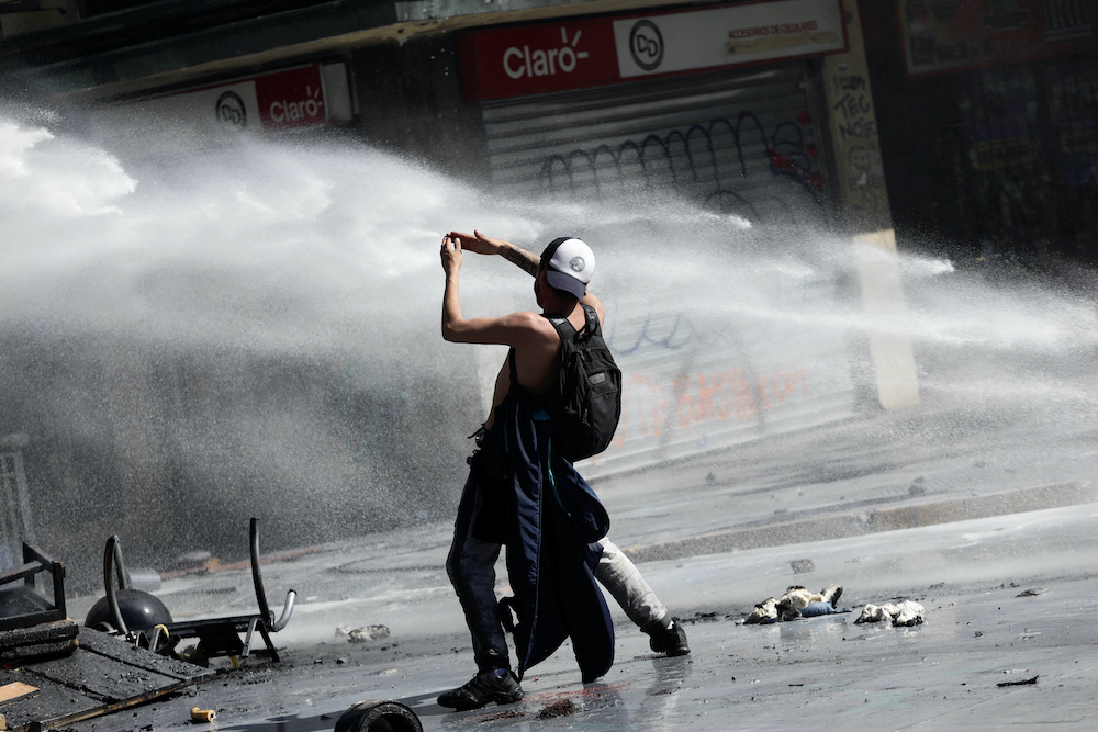 A demonstrator gestures next to a jet of water released from a riot police vehicle during a protest against Chile's state economic model in Concepcion, Chile October 23, 2019. u00e2u20acu201d Reuters pic