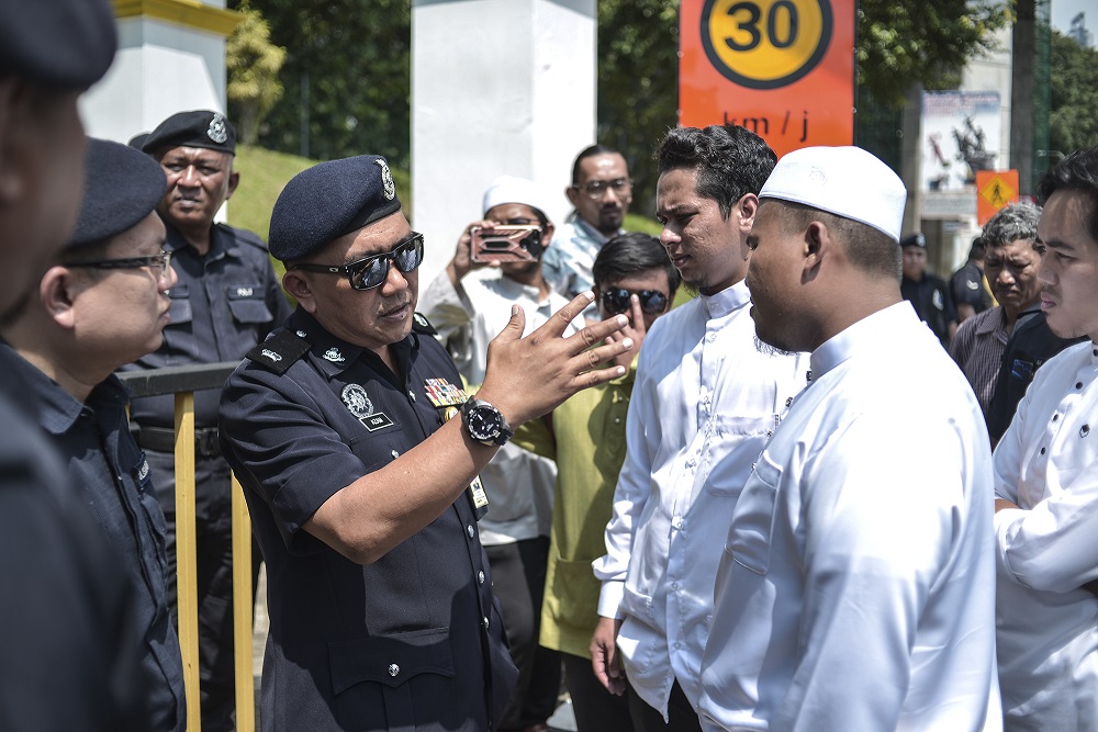 A police officer speaks to the students in front of Universiti Malaya in Kuala Lumpur October 25, 2019. — Picture by Shafwan Zaidon
