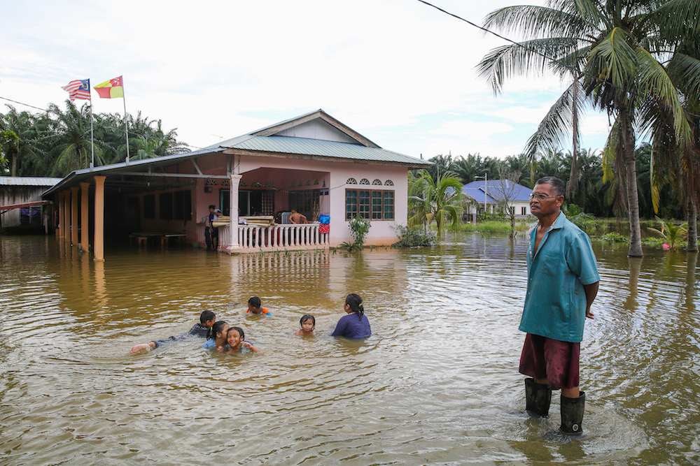 Mohd Misnan Lagiman checks on his home as kids play in floodwater in Kampung Parit Mahang, Jeram October 28, 2019. — Picture by Yusof Mat Isa