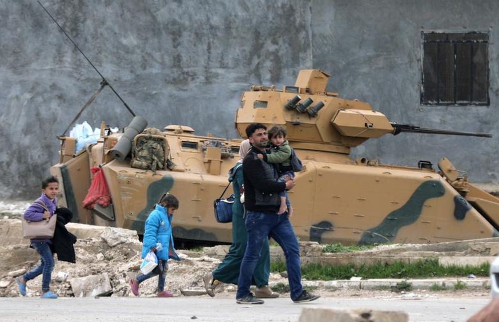 A family walks past a military vehicle belonging to Turkish-backed Free Syrian Army fighters after the capture of Khaldieh village, in eastern Afrin, Syria March 10,2018. u00e2u20acu201d Reuters pic