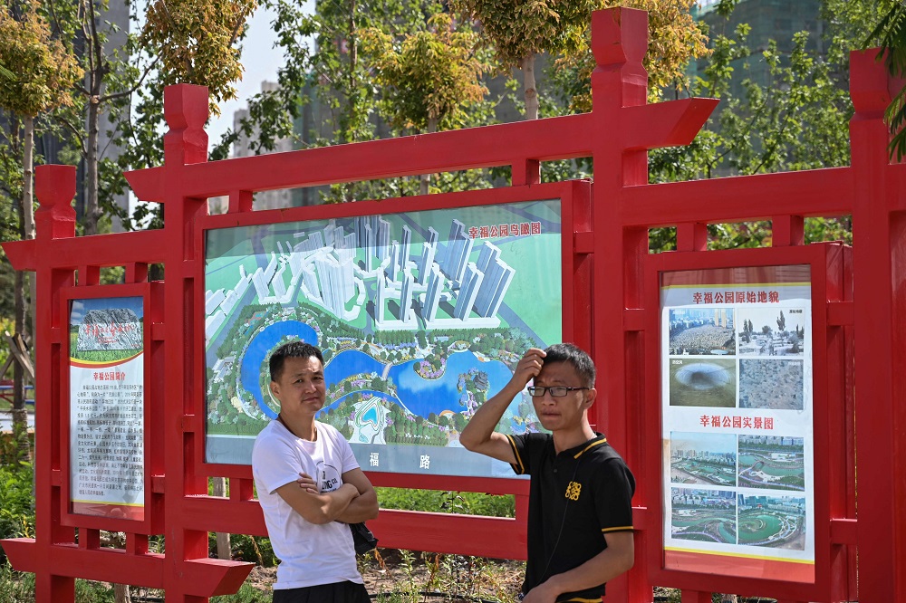 This photo taken on September 14, 2019 shows a sign at the entrance of ‘Happiness Park’ where a Uighur cemetery used to be displaying before and after photos of the site in Aksu in the region of Xinjiang. ― AFP pic  