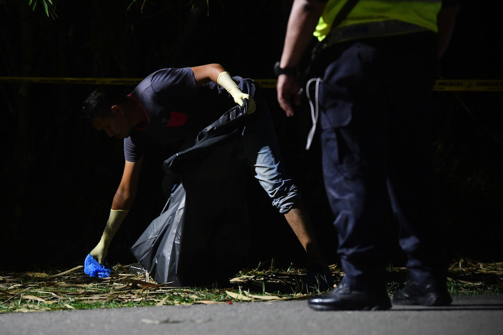 A policeman recovers a dismembered body part in Kampung Ladang Krubong, Melaka October 10, 2019. — Bernama pic