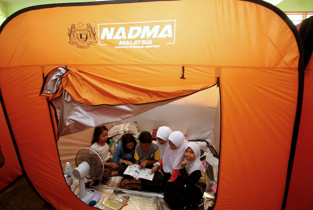 Children read a book as they seek shelter at a temporary relief centre at SK Changkat Jong in Teluk Intan October 24, 2019. u00e2u20acu201d Bernama pic