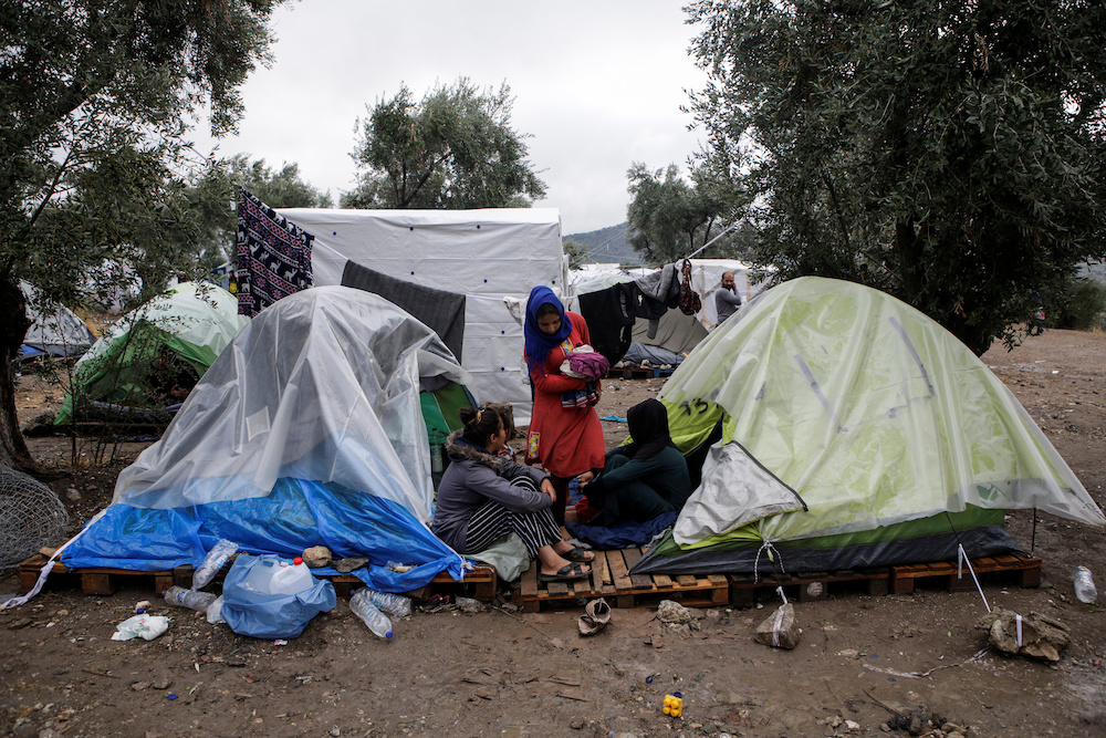 Women sit outside their tents at a makeshift camp for refugees and migrants next to the Moria camp, following a rainfall on the island of Lesbos, Greece, October 8, 2019. u00e2u20acu201d Reuters picnn