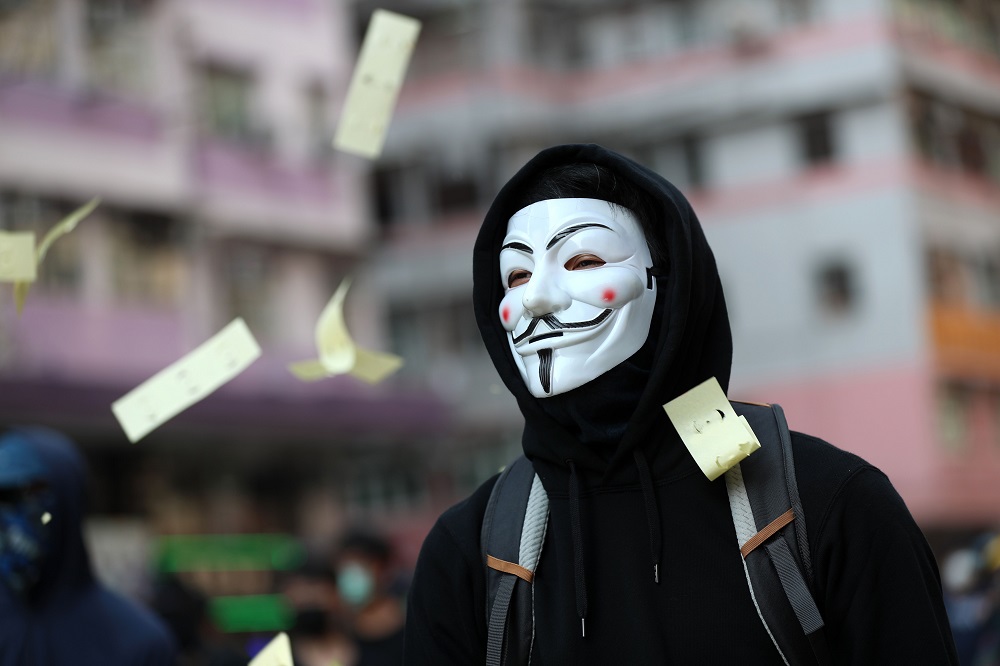 Ceremonial u00e2u20acu02dcjoss paperu00e2u20acu2122 used in memory of those who died for democracy flutters around a protester wearing a Guy Fawkes mask during a demonstration in the Sham Shui Po district in Hong Kong on October 1, 2019. u00e2u20acu201d AFP pic