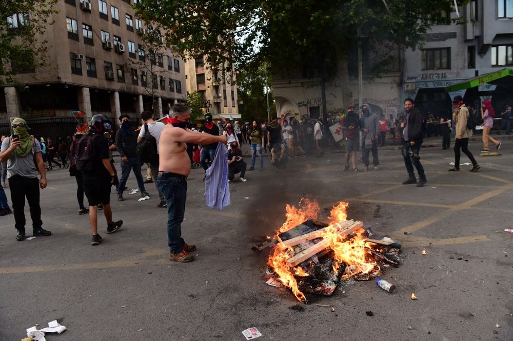 A demonstrator tries to get his shirt dried next to a bonfire during the so-called u00e2u20acu02dcMourning Marchu00e2u20acu2122 in Santiago on November 01, 2019, to protest against the death of 23 people after more than ten days of civil unrest. u00e2u20acu201d AFP pic
