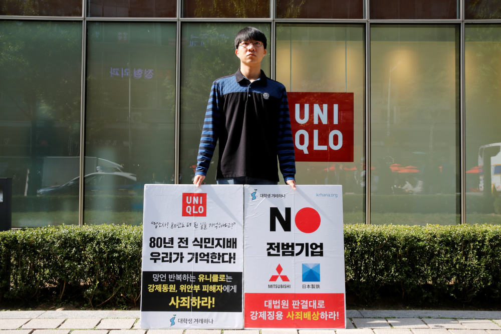 University student Bang Seulkichan stands with banners as a protest against recent released Uniqlo commercial in front of a Uniqlo store in Seoul, South Korea, October 22, 2019. The banner reads u00e2u20acu02dcColonial rule 80 years ago u00e2u20acu201c we remember!u00e2u20acu2122 u00e2u20acu201d Reuter