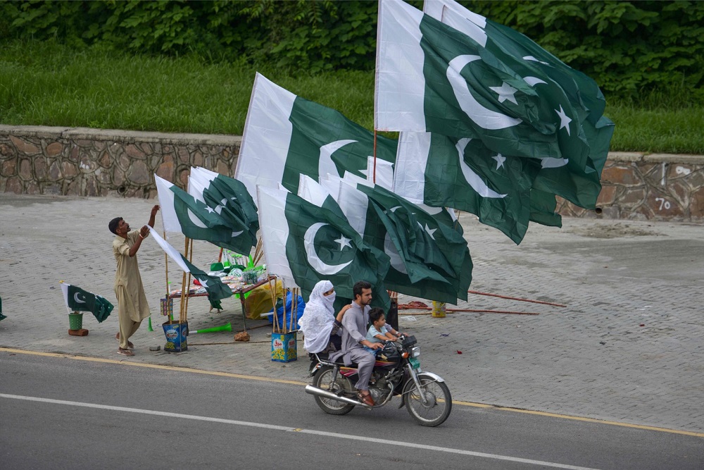 A family rides past a Pakistan national flag stall set for the upcoming Independence Day celebration in Islamabad August 7, 2019. u00e2u20acu201d AFP pic