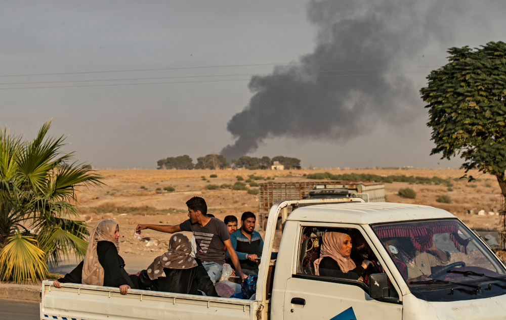 Syrians ride a pickup truck past smoke as Arab and Kurdish civilians flee following Turkish bombardment on Syriau00e2u20acu2122s northeastern town of Ras al-Ain in the Hasakeh province along the Turkish border October 9, 2019. u00e2u20acu201d AFP pic 
