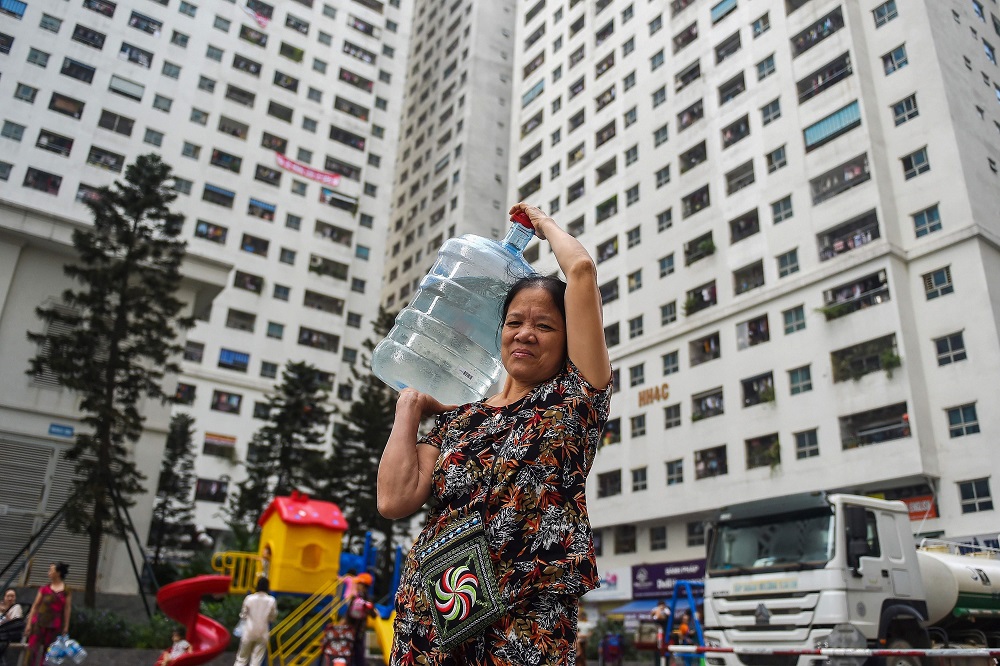 A Vietnamese resident carries water filled container supplied by a government tanker after tap water contamination in some areas of Hanoi on October 17, 2019. u00e2u20acu201d AFP pic