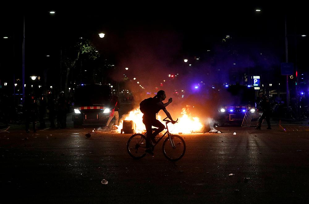 A man rides his bicycle past a fire during a protest after a verdict in a trial over a banned independence referendum in Barcelona, Spain October 15, 2019. u00e2u20acu201d Reuters pic