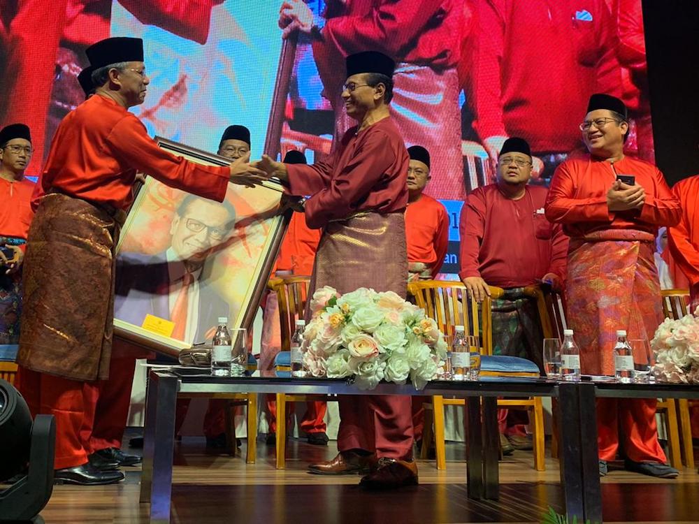Johor Umno chairman Datuk Hasni Mohammad (far left) presents a portrait to Umno veteran Tan Sri Abdul Ghani Othman (centre) during the Johor Umno Convention 2019 in Johor Baru October 5, 2019. — Picture by Ben Tan