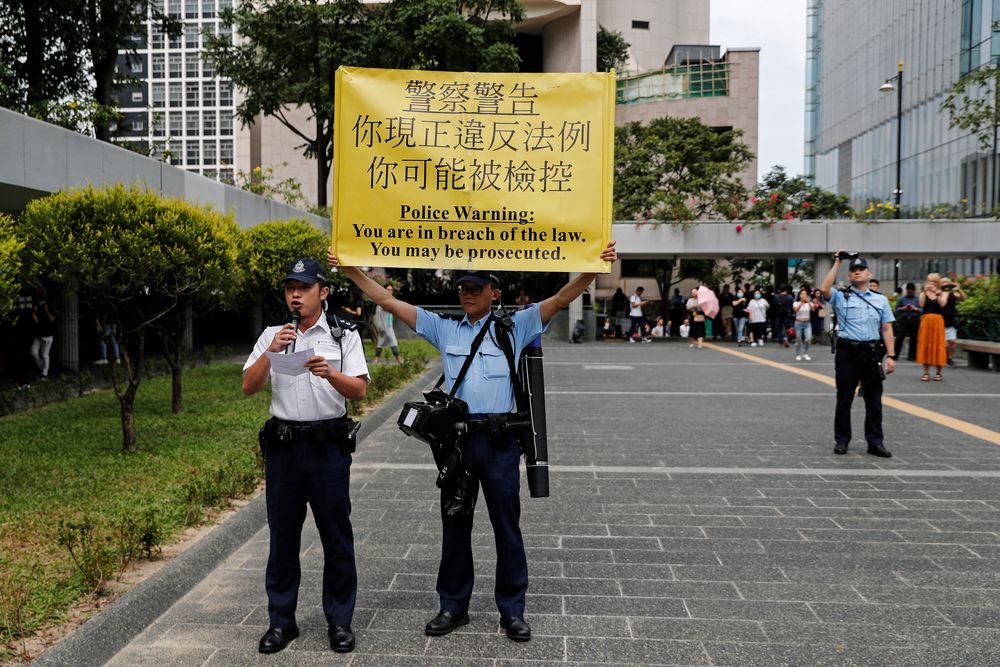 A policeman holds a sign while another warns people marching to protest against what they say is the abuse of pro-democracy protesters by Hong Kong police, at Chater Garden in Central district, Hong Kong, China October 18, 2019. u00e2u20acu201d Reuters pic