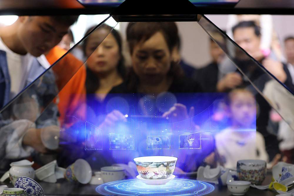 Visitors hold their phones in front of a hologram showing a porcelain teacup that is projected inside a glass cabinet during the World Conference on VR Industry in Nanchang, Jiangxi province, China October 20, 2019. u00e2u20acu201d  Reuters pic