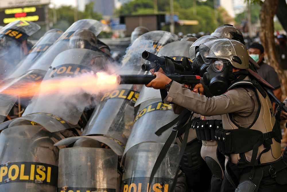 A riot police officer fires tear gas during a riot following protests near Indonesian Parliament building in Jakarta September 30, 2019. u00e2u20acu201d Antara Foto/Aditya Pradana Putra pic via Reuters