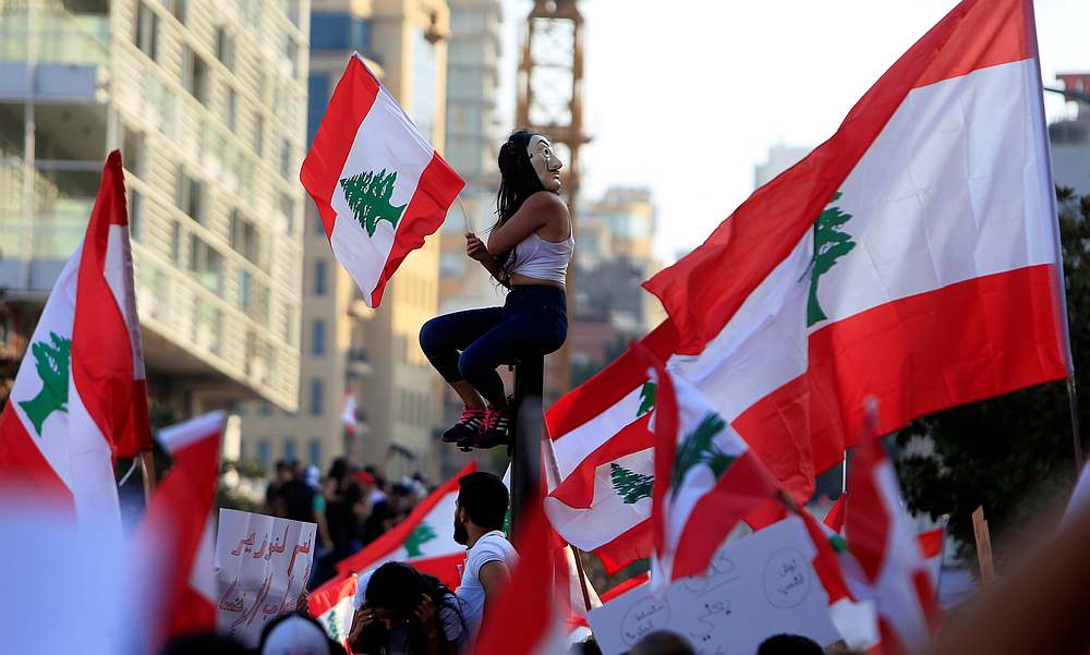 A demonstrator sits on a pole while carrying a national flag during an anti-government protest in downtown Beirut, Lebanon October 20, 2019. u00e2u20acu201d Reuters pic 