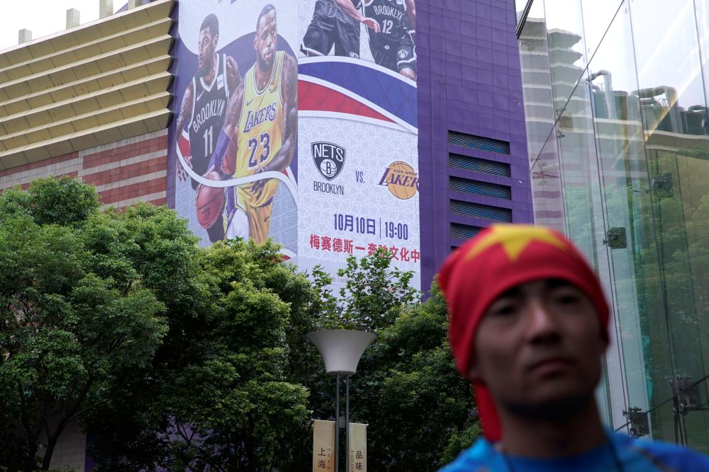 A man with his head wrapped in a Chinese national flag is seen near a building with a partly-removed banner advertising an NBA China game between Brooklyn Nets and Los Angeles Lakers, in Shanghai October 9, 2019. u00e2u20acu201d Reuters pic