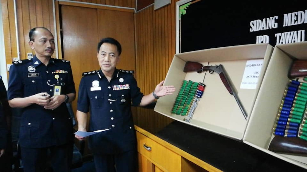 Peter Umbuas (2nd right) showing some of the weapons and guns that were believed to be used by the suspects behind the merciless killing of a juvenile elephant in Sabah.