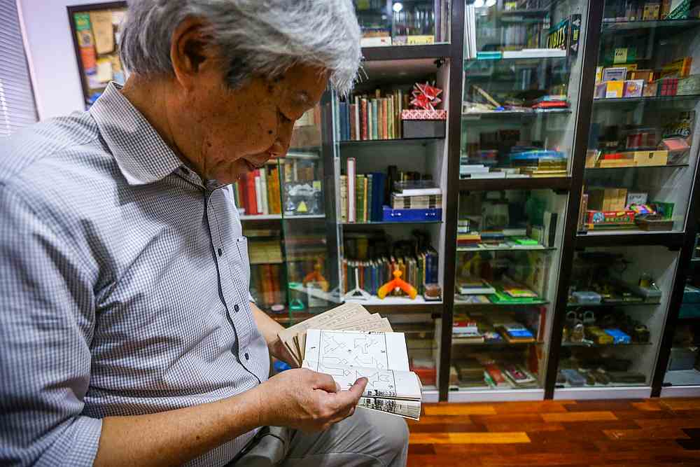 Lee flipping through the rare tangram puzzle book set, which cost him a cool RM3,000. — Picture by Hari Anggara