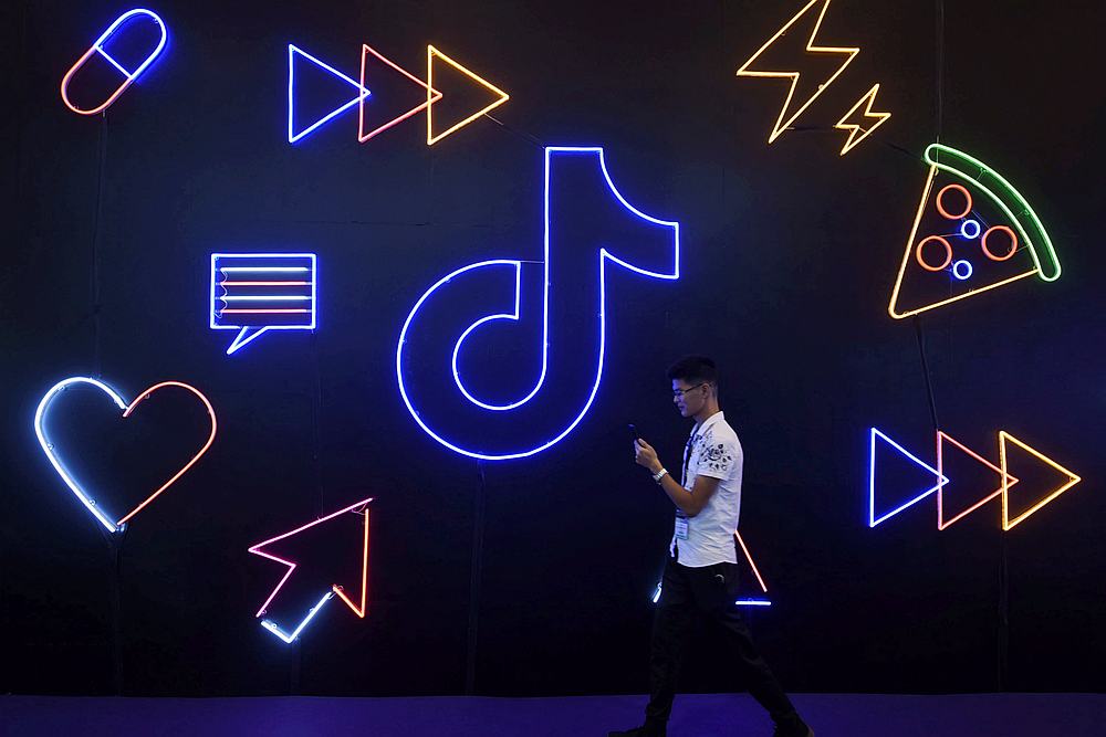 A man holding a phone walks past a sign of Chinese company ByteDance's app TikTok, known locally as Douyin, at the International Artificial Products Expo in Hangzhou, China October 18, 2019. u00e2u20acu201d Reuters pic
