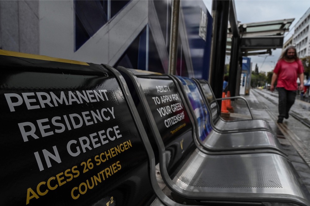 A man walks past sits at a tram station decorated with Golden visa advertisements aiming Chinese clientele in central Athens October 31, 2019. u00e2u20acu201d AFP pic