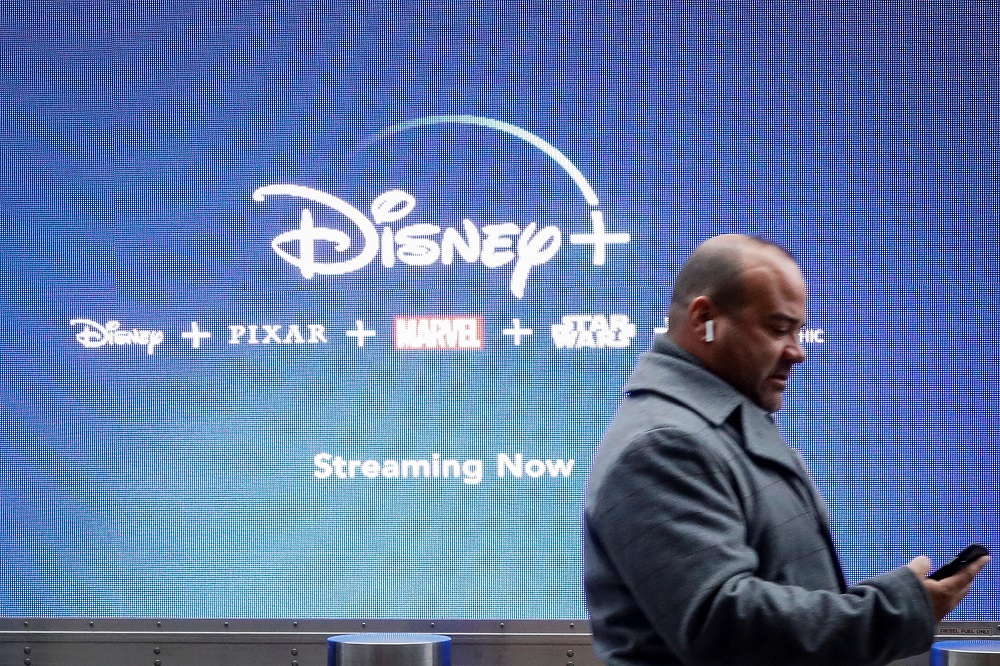 A man looks at his phone as he passes by a screen advertising Walt Disney's streaming service Disney+ in New York November 12, 2019. u00e2u20acu201d Reuters pic