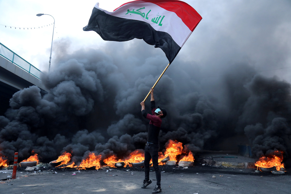 A protester holds an Iraqi flag next to burning tires during ongoing anti-government protests in Kerbala, Iraq November 27, 2019. u00e2u20acu201d Reuters pic