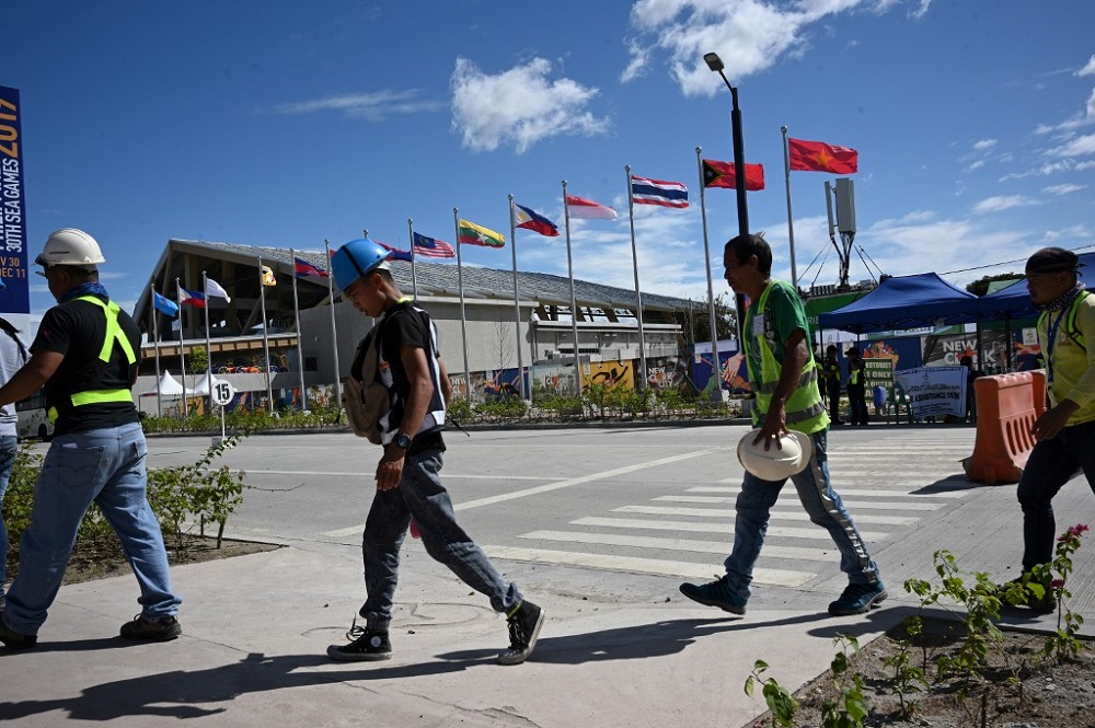 Workers walk past Asean membersu00e2u20acu2122 flags next to the Aquatic centre in New Clark City, in Capas town, Tarlac province north of Manila November 26, 2019. u00e2u20acu201d AFP pic