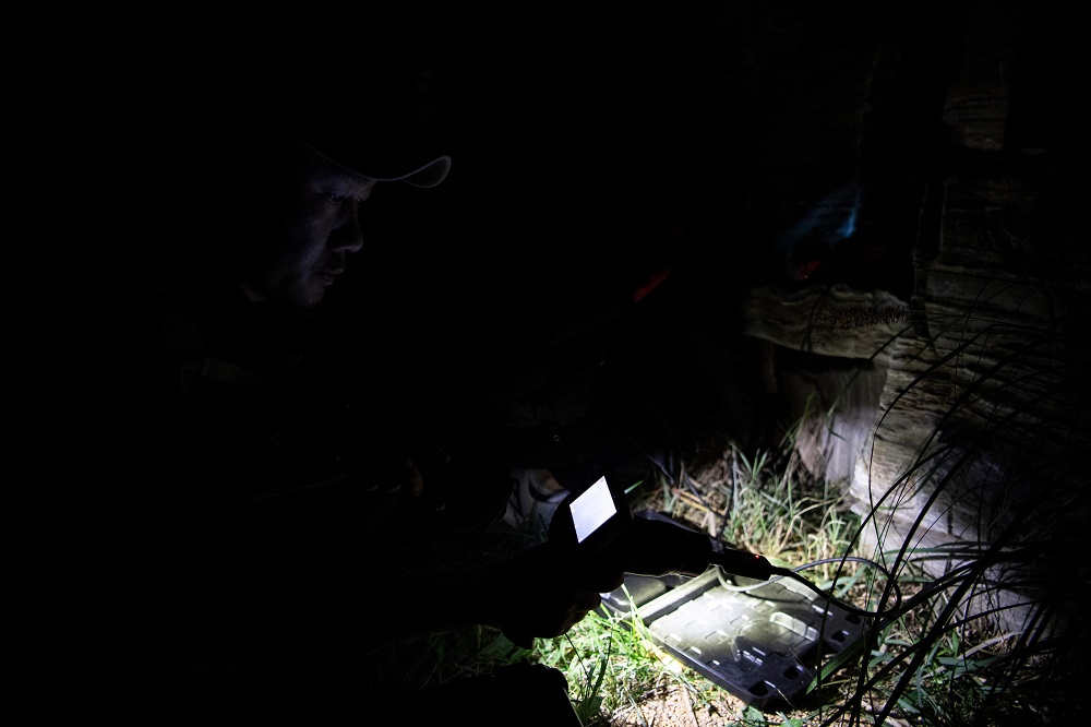 This photo taken on October 23, 2019 shows pet detective Sun Jinrong using a night vision camera as he searches for a missing cat in a residential compound in Beijing. — AFP pic  