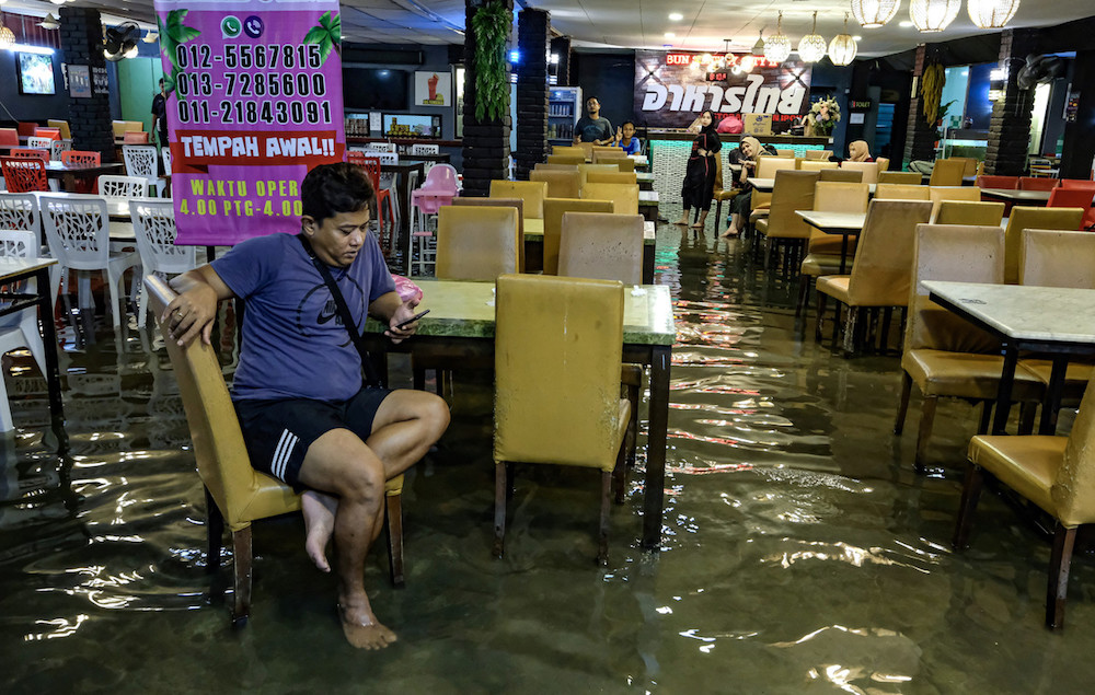 A man uses his mobile phone in a restaurant in Ipoh November 1, 2019, during a flash flood. u00e2u20acu201d Bernama pic