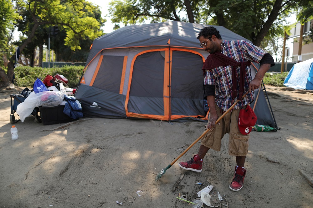 Everett Gutierrez, 31 who is homeless, rakes outside the tent in which he lives in Los Angeles, California October 14, 2019. ― Reuters pic