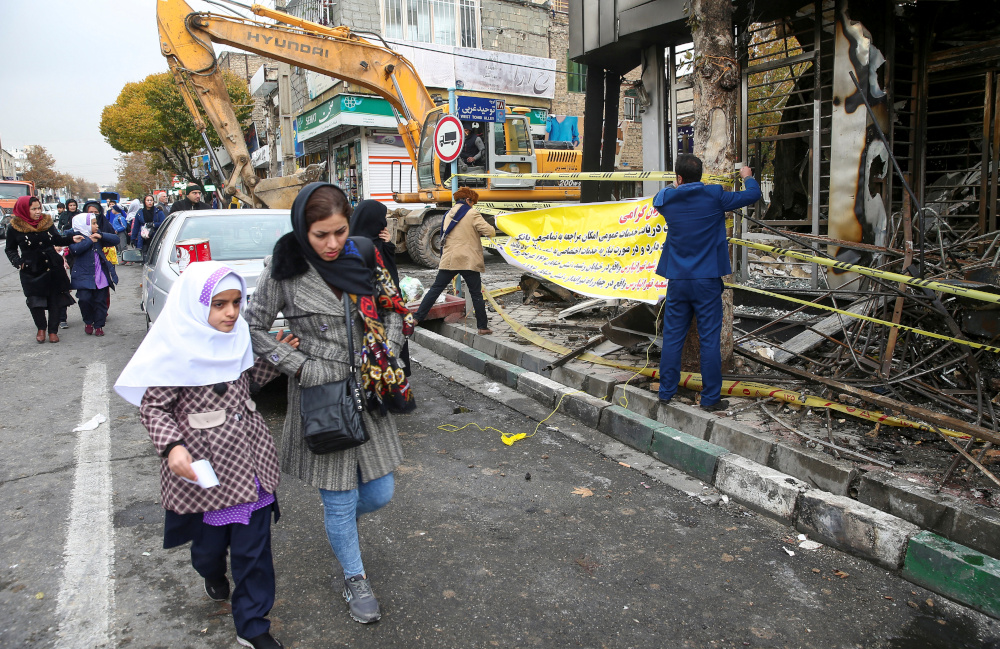 People walk near a burnt bank, after protests against increased fuel prices, in Tehran, Iran November 20, 2019. u00e2u20acu201d Nazanin Tabatabaee/West Asia News Agency handout pic via Reuters 