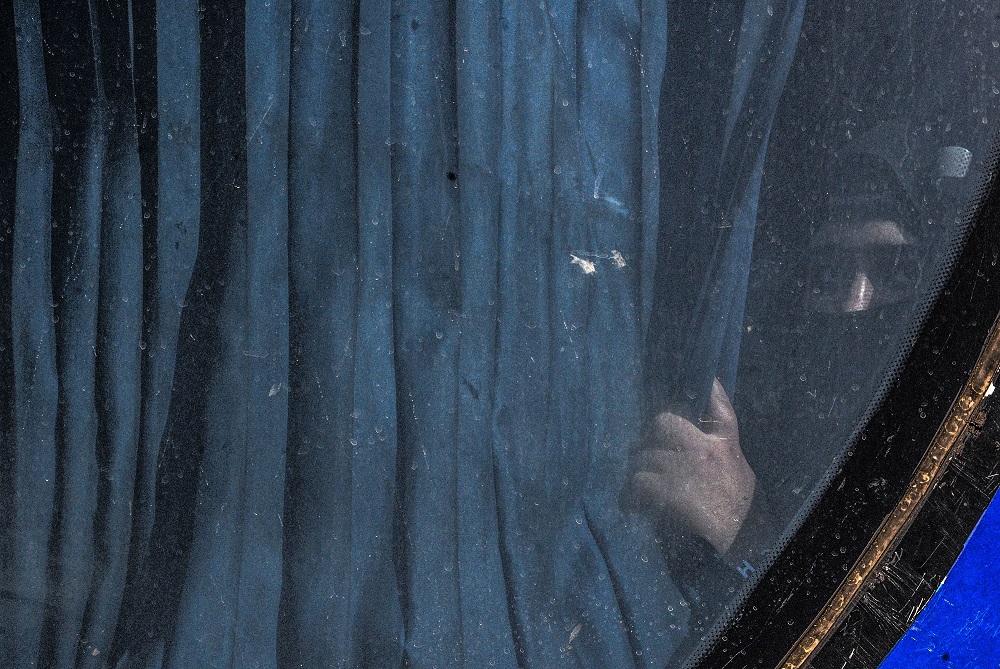 A displaced Iraqi peaks from behind a curtain on board a bus at a camp for displaced people in Hammam al-Alil, south of the northern Iraqi city of Mosul, on August 27, 2019, as they are transferred back to Kirkuk province. u00e2u20acu201d AFP pic 