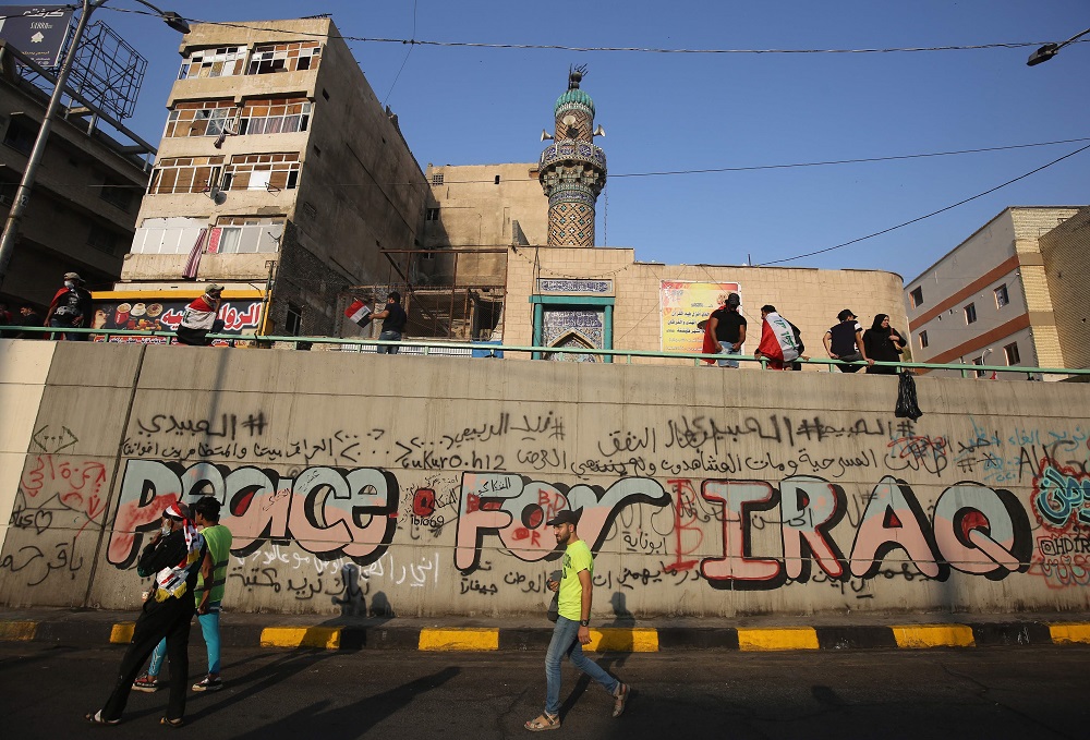 Iraqi demonstrators walk by a graffiti-filled wall in Tahrir square in the capital Baghdad on November 3, 2019, amid ongoing anti-government protests. u00e2u20acu201d AFP pic 