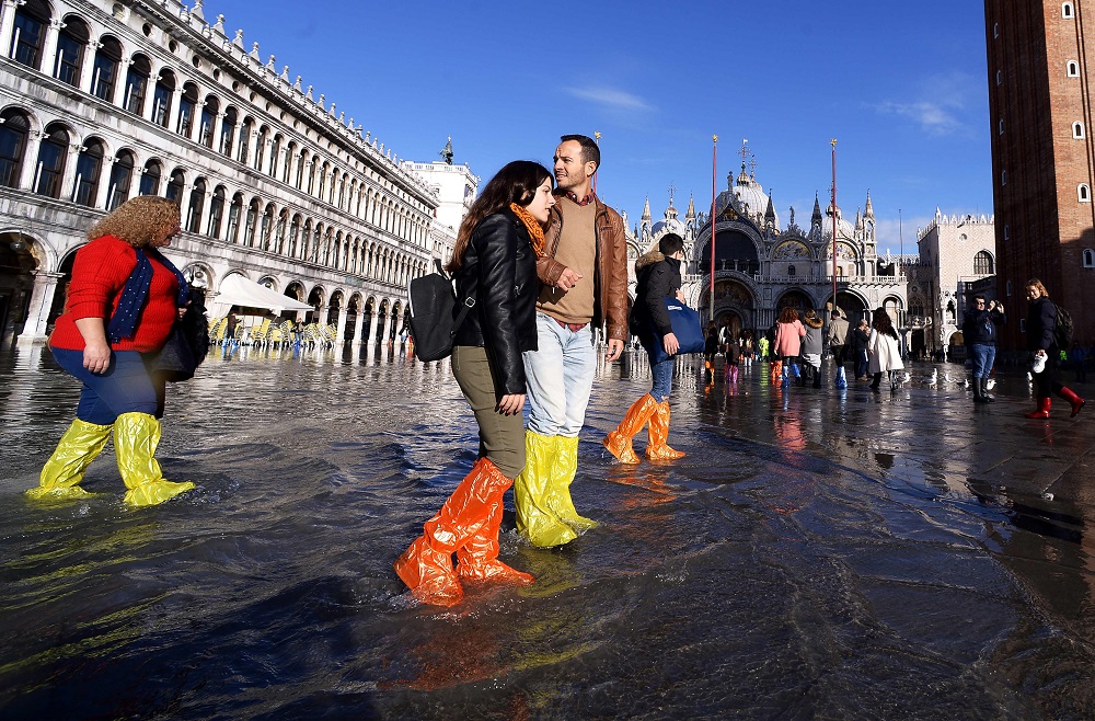 People wearing waterproof shoe covers walk across the flooded St Marku00e2u20acu2122s Square, with St Marku00e2u20acu2122s Basilica (rear) in Venice November 14, 2019. u00e2u20acu201d AFP pic